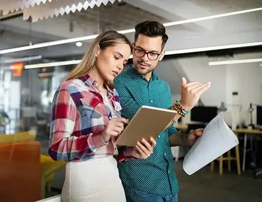 Two colleagues reviewing plans together on a tablet in an open office