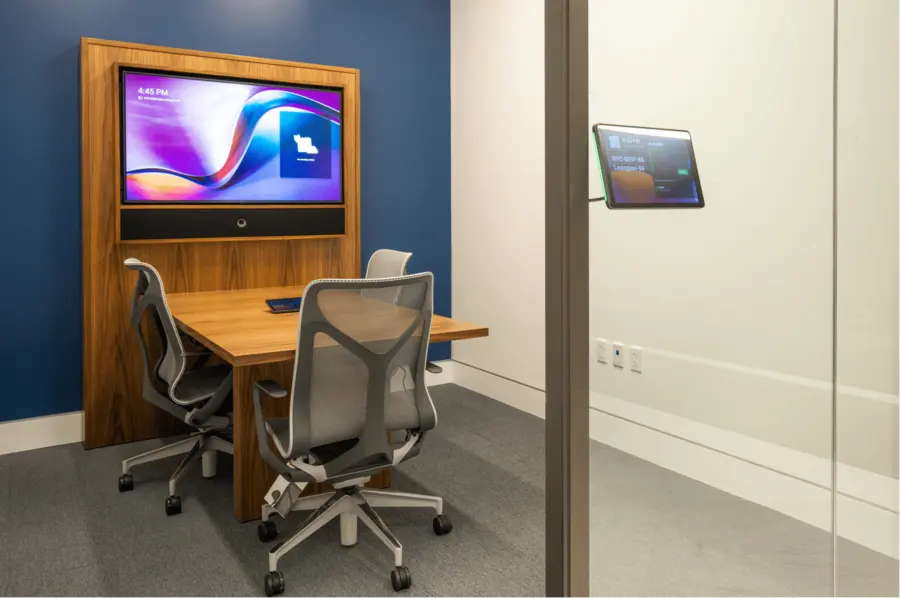 Two person focus room with a wall display, camera, and a scheduling panel outside the glass